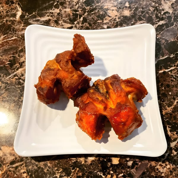 Two pieces of Safari77 Cuisine's fried African chicken on a white rectangular plate.
