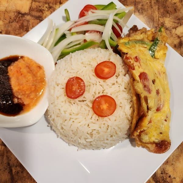 Safari77 Cuisine's African dish with white rice, omelet, fresh salad, and a side of sauce.