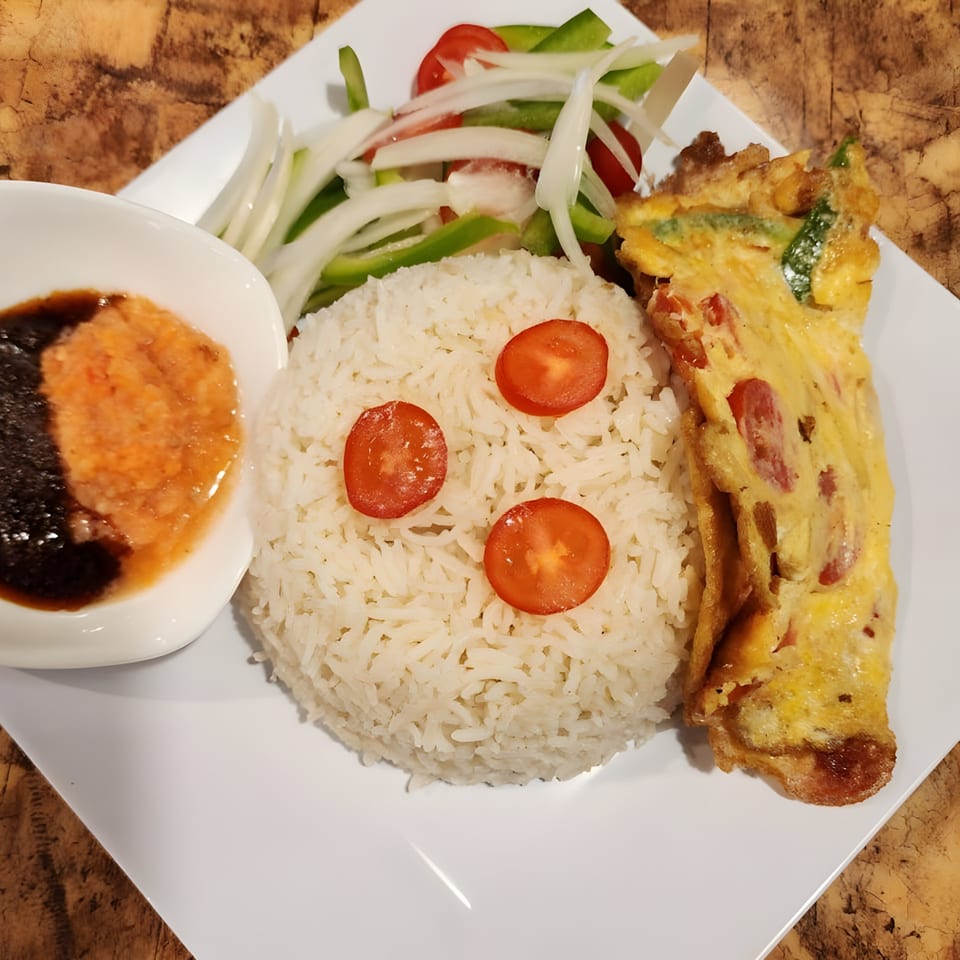 Safari77 Cuisine's African dish with white rice, omelet, fresh salad, and a side of sauce.